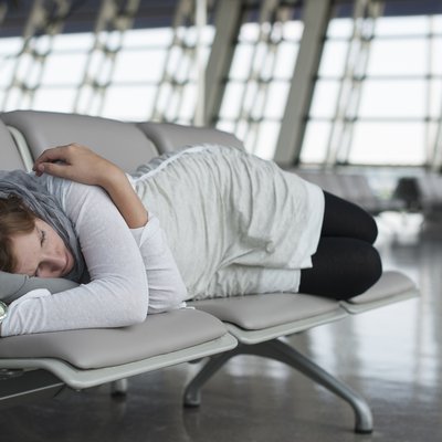 Erschöpfte Passagierin schläft auf Sitzreihe in der Wartehalle