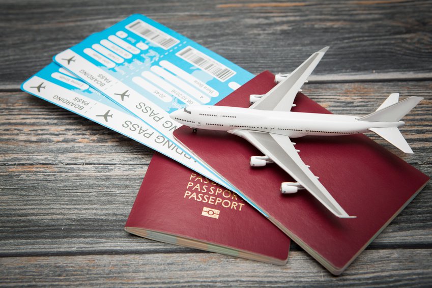 Reisepass mit zwei Flugtickets und Miniatur-FLugzeug