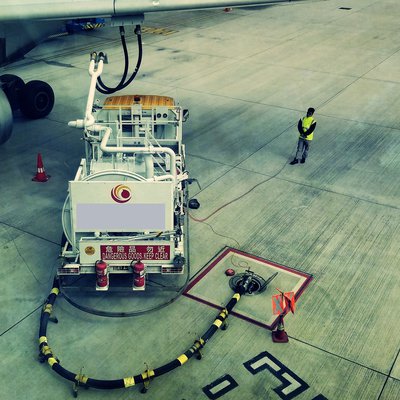 Tankwagen unter einer Tragfläche bei der Betankung eines Flugzeuges auf einem Flugfeld