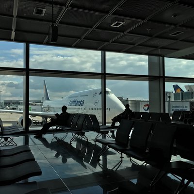Wartebereich im Terminal mit Glasfront, dahinter: Lufthansa-Maschine