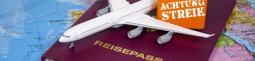 Reisepass und Miniatur-Flugzeug mit "Achtung Streik"-Schild liegen auf einer Landkarte