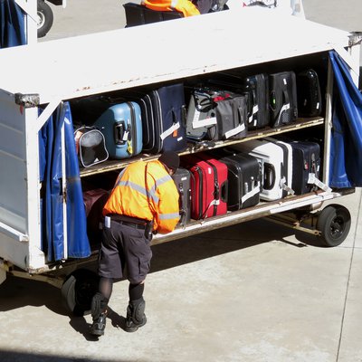 Mitarbeiter an Kofferwagen auf dem Flugfeld