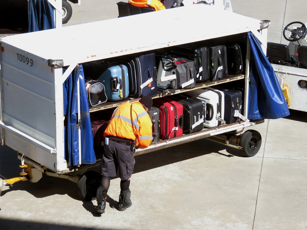 Mitarbeiter an Kofferwagen auf dem Flugfeld