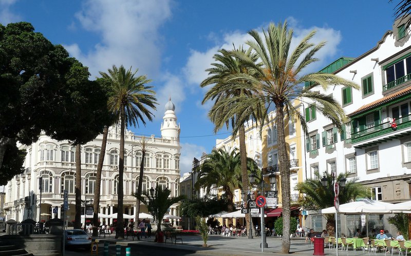 Ein Marktplatz mit Gebäude und Palmen drumherum