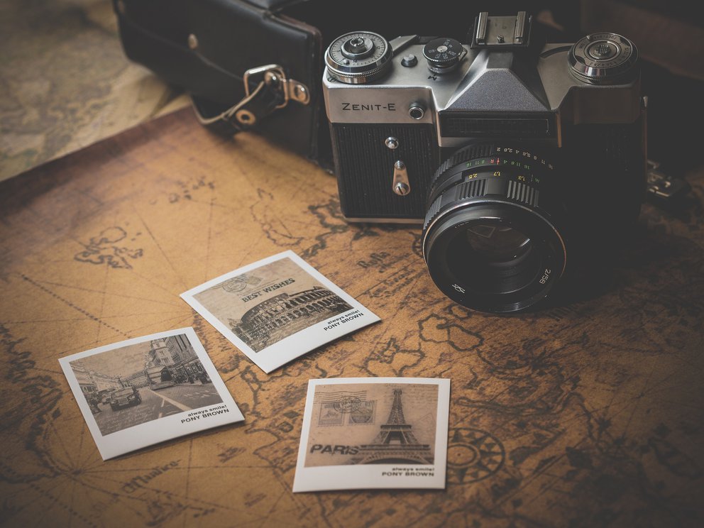 Alter Fotoapparat auf einer Landkarte mit Polaroidfotos