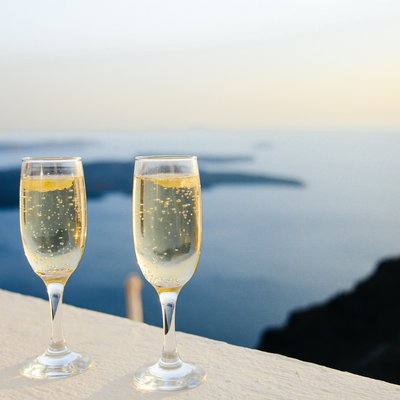 Zwei Champagner-Gläser auf einer hellen Mauer mit dem Meer im Hintergrund