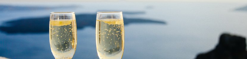 Zwei Champagner-Gläser auf einer hellen Mauer mit dem Meer im Hintergrund